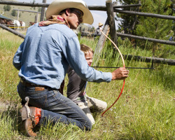 A Ranch Hand Shows a Little Boy How to Safely Shoot an Arrow at Triangle C Ranch